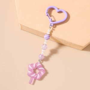 Detail of purple star candy keychain with white pearls and heart clasp on beige background