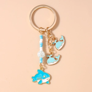 Detail of shark and dolphin pendants on blue beaded keychain with gold ring