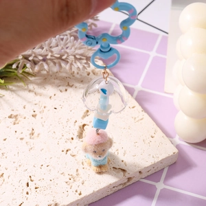 Detailansicht niedlicher Plüschwelpen-Schlüsselanhänger mit blauem Karabiner und Glöckchen