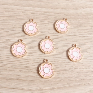 Detailed view of pink enamel doughnut charms with gold edges and bite marks for DIY crafts