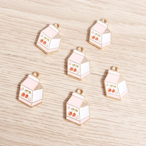 Detailed view of pink cherry milk box charms for DIY jewelry on wooden background