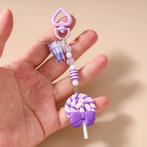 Close-up of a purple lollipop keychain with striped beads and a miniature milk tea charm