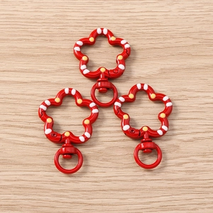 Close-up of three red floral spring ring keychains with polka dots on wooden surface