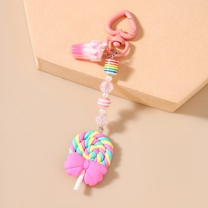 Detail of colorful polymer clay lollipop keychain with striped beads and a pink heart clip