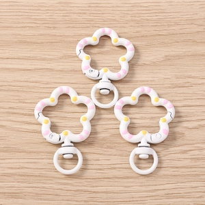 Macro detail of white flower-shaped metal keychains with pink and yellow polka dots