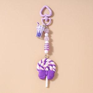 Detail of purple polymer clay lollipop keychain with striped beads and bubble tea charm