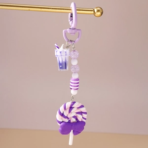 Detail of purple clay lollipop keychain with striped beads and a mini milkshake charm