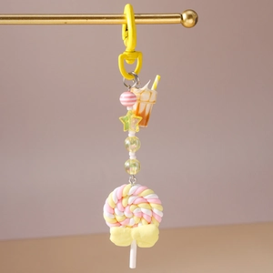 Close-up of a colorful polymer clay lollipop keychain with striped beads and a yellow bow