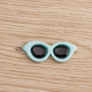 Macro-detail van een lichtblauwe cat-eye hanger met een zilveren metalen ophangring