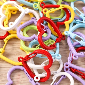 Macro detail of colorful heart-shaped snap hooks with spring gate on wood background