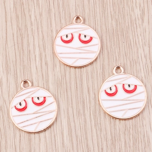 Gros plan de breloques momie en or rose avec émail blanc pour bijoux artisanaux