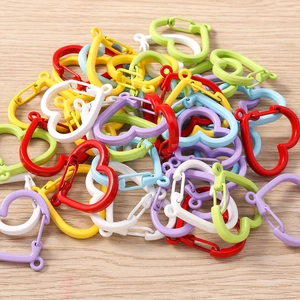 Macro shot of assorted colorful heart-shaped spring snap hooks on light wood background