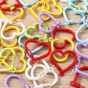 Close-up of heart-shaped metal lobster clasps in colorful matte finishes on wood background