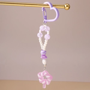 Detail eines lila Herz-Haken-Anhängers mit Perlen und rosa Lutscher-Süßigkeiten