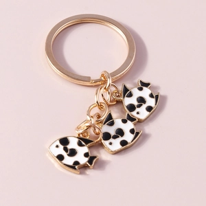 Detail of three gold-plated enamel fish charms on a keychain with a checkerboard pattern
