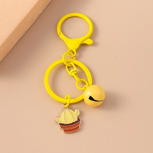 Cute yellow keychain with cactus plant pendant and mini bell on a pink background