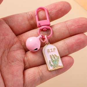Porte-clés tombeau rose créatif avec main de crâne RIP et clochette tenu à la main