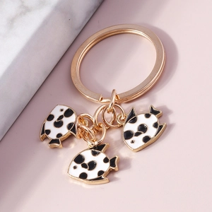 Close-up of golden goldfish keychains with black and white spotted enamel fish charms