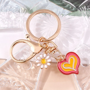 Golden keychain with a daisy flower charm and a pink heart pendant on embossed glass