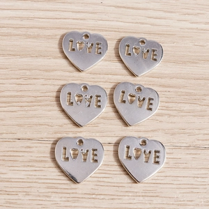 Detailed close-up of six heart-shaped LOVE charms for DIY jewelry making and crafts