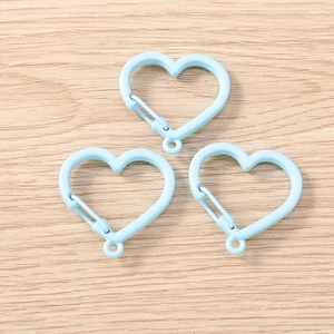 Three sky blue heart-shaped carabiners with spring gates on light wood background