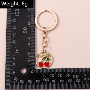 Détail du porte-clés cerise rouge pesant 6g avec anneau doré et finition émaillée