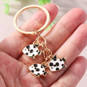 Fashionable gold metal fish keychain with black spotted panda fish charms on hand