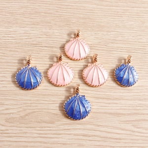 Pink and dark blue enamel shell charms with golden alloy edges on a wooden background