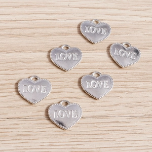 Macro shot of silver heart pendants with LOVE engraving on a natural wood surface