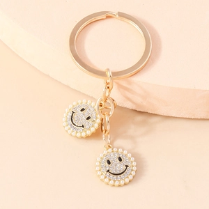 Golden keychain with rhinestone smile pendants and elegant pearls on geometric stand