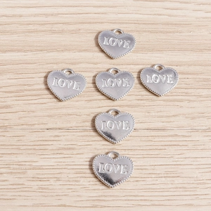 Macro shot of silver plated heart charms with LOVE engraving for DIY jewelry