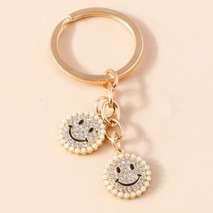 Golden keychain with rhinestone pavé smiley face charm and white pearl border detail