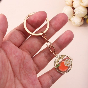 Vue détaillée d'un porte-clés motif orange en émail avec une finition dorée
