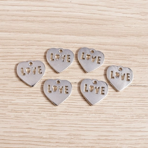Close-up of heart-shaped LOVE charms in polished silver finish for DIY jewelry