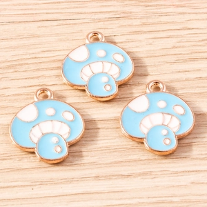 Three light blue mushroom pendants with gold edges for DIY jewelry making on wood background