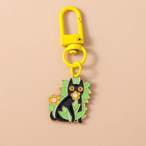 Détail d'un porte-clés chat noir avec fleur et boucle en forme de D au fini doré