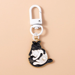 Détail du porte-clés chat Yin Yang en émail avec motifs soleil et lune sur fond orange