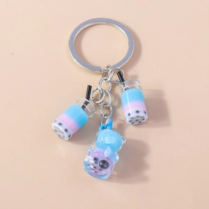 Detail of boba tea and blue bear charms on a colorful resin keychain with silver ring