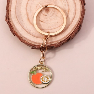 Gros plan d'un porte-clés doré avec design orange en émail et pendentif ajouré rond
