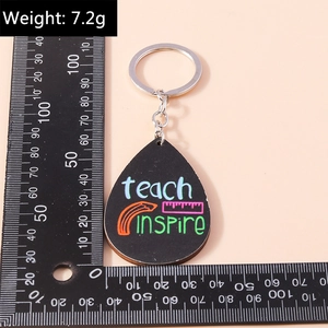 Close-up of teardrop teacher keychain featuring colorful teach and inspire text and ruler