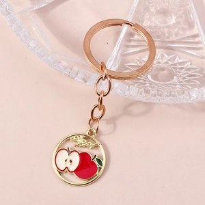 Vue macro d'un porte-clés doré avec pendentif pomme évidé et finition émail rouge