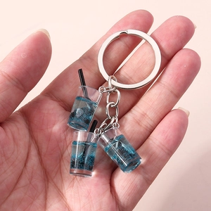 Detail von blauem Bubble-Tea-Schlüsselanhänger mit Glitzerflüssigkeit auf rosa Grund