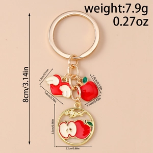Detail view of apple themed keychain with gold plating and red enamel charms