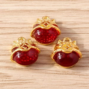Three Chinese style fox and cat gold charms with red gemstone inlay on wood background
