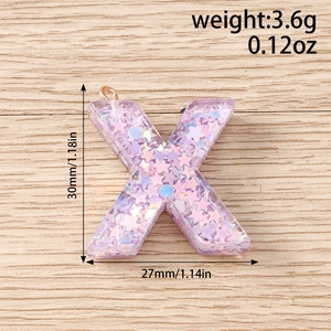 Detailed view of translucent purple resin letter X pendant with glitter and gold ring