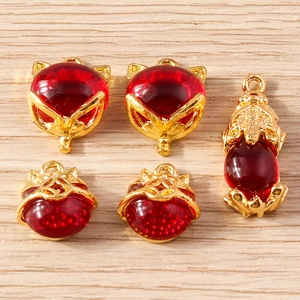 Detailed close-up of 5 red and gold Chinese fox and coin pendants for DIY jewelry