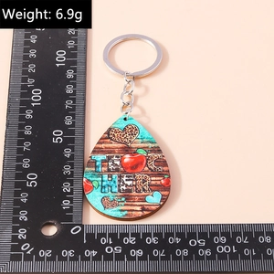 Detailed view of teardrop wooden teacher keychain with 'TEACHER' print and a scale ruler