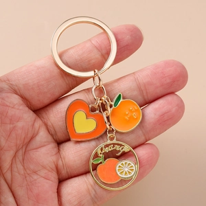 Detailed view of an orange fruit keychain with heart charm and 'Orange' gold pendant