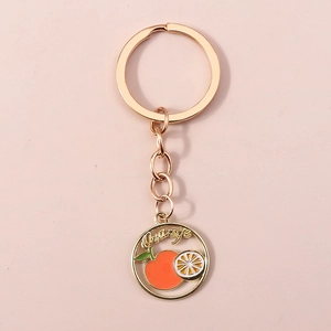 Détail d'un porte-clés orange plaqué or avec tranches d'agrumes et petite feuille verte