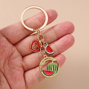 Detailed close-up of a gold alloy watermelon keychain with heart and fruit pendants